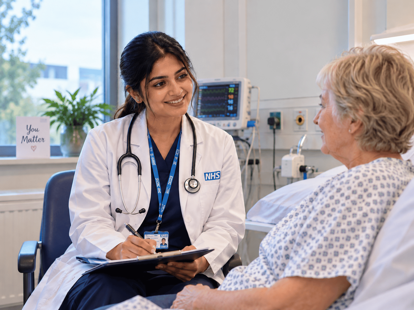 A clinician speaking with a patient in a hospital room.